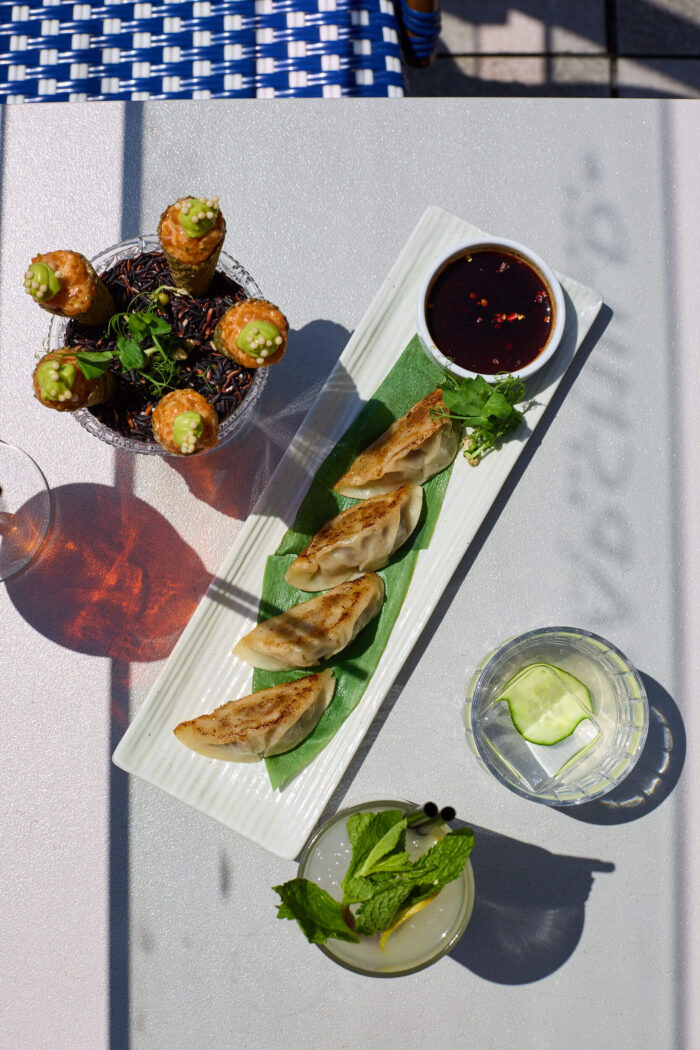 Outdoor table with dumplings, cocktail cones, and drinks at Starchild Rooftop.