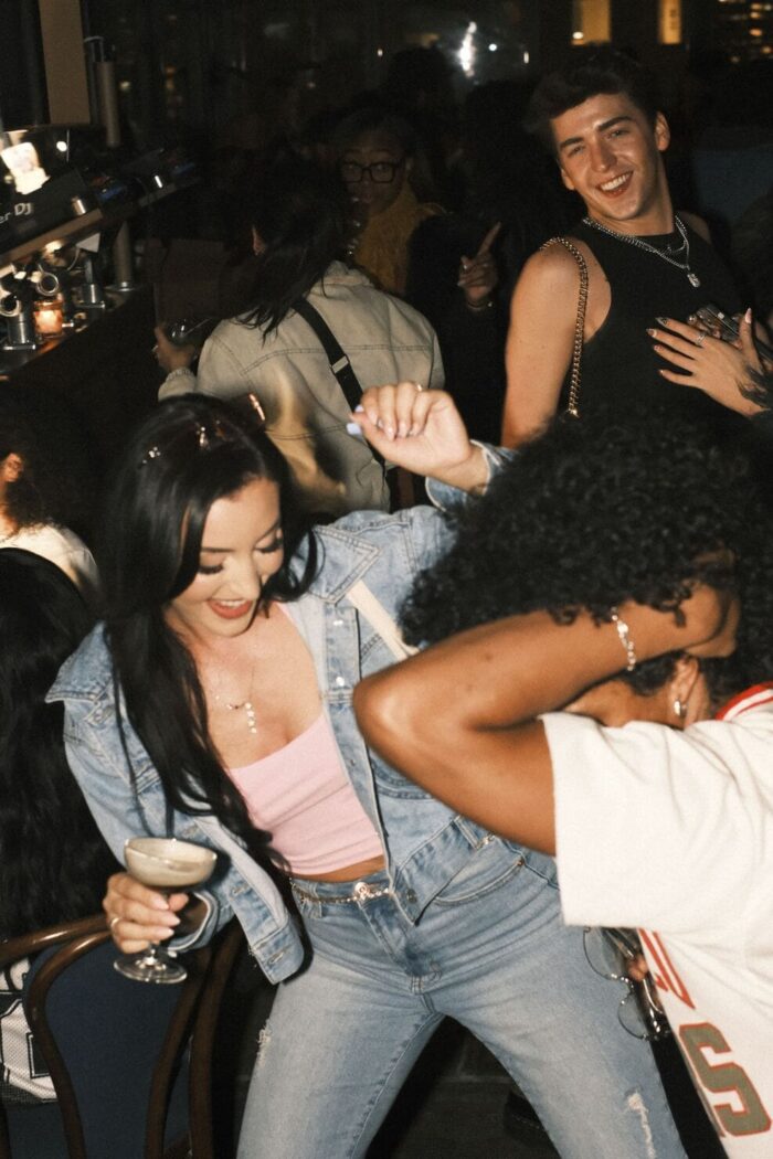 Group of people dancing and enjoying cocktails at a lively nightlife event