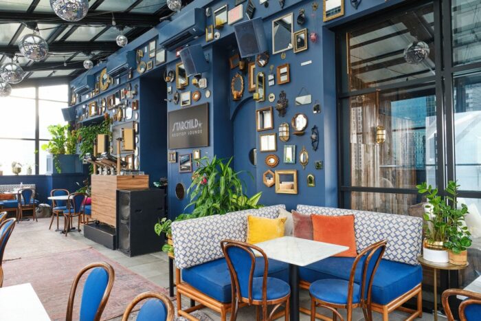 Stylish indoor seating area at Starchild Rooftop Lounge with blue walls, framed mirrors, and disco balls.